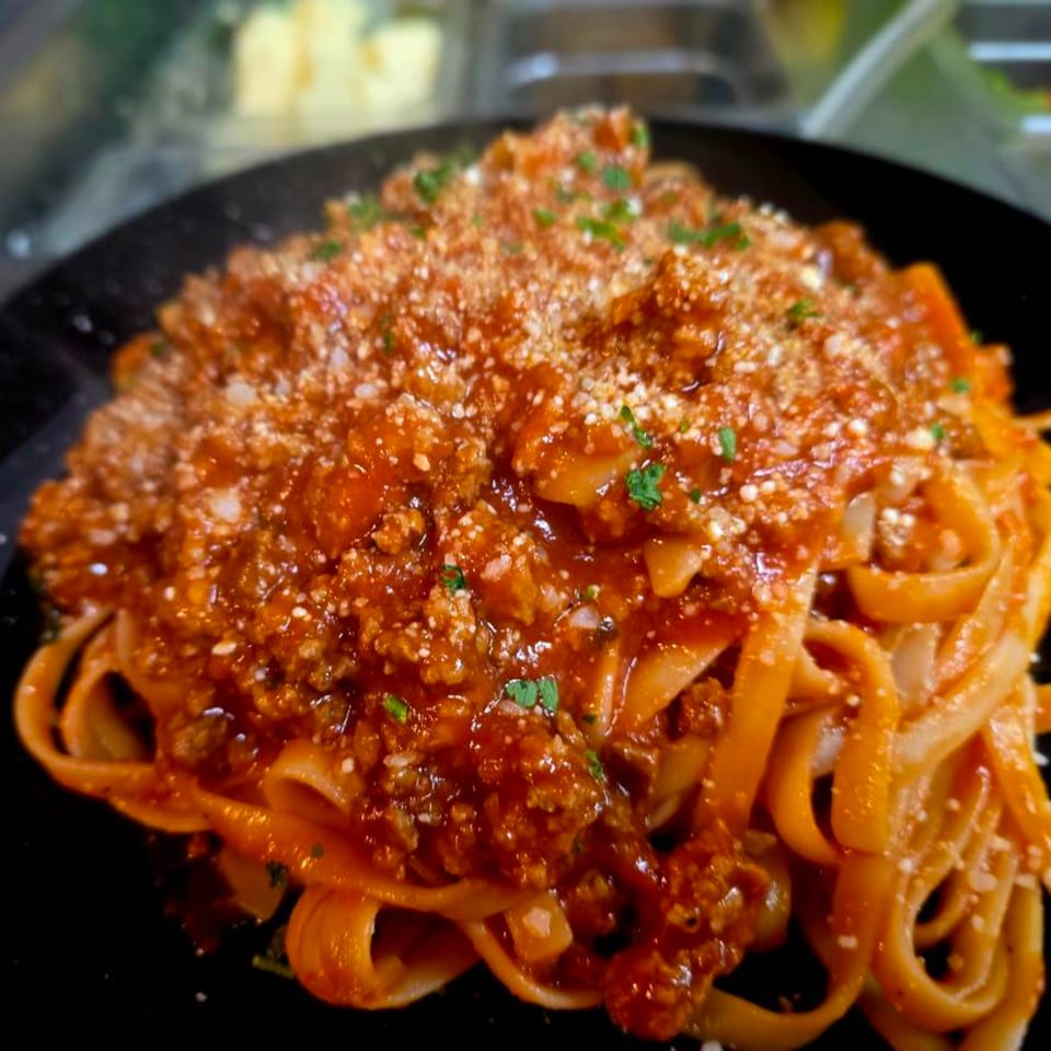 Buona Cucina Italiano's fettuccine pasta with rich red bolognese sauce, grated cheese, and fresh parsley.